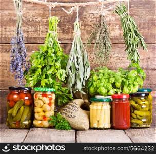 various fresh herbs and canned food on wooden background