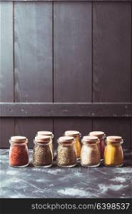 Various grinded spices in vintage glass bottles over wooden wall, copy cpase. Various grinded spices