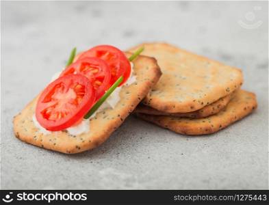 Various healthy crackers with cream and tomato on light kitchen table background.