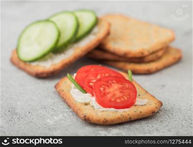 Various healthy crackers with cream and tomato with cucumber on light kitchen table background.