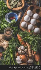Various ingredients for tasty paleo diet. Healthy natural organic food concept. Carrots, onions, eggs, ginger roots vegetables, seasonings on dark rustic kitchen table background , top view.
