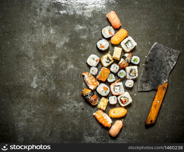 Various Japanese sushi rolls with an axe for cutting. On the stone table.. Various Japanese sushi rolls with an axe for cutting.