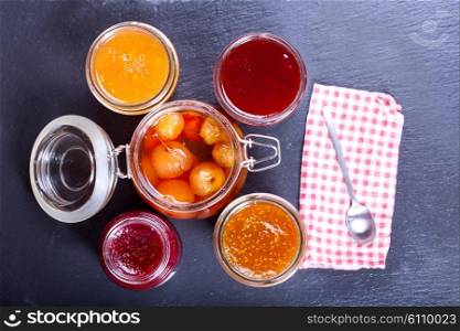 various jars of fruit jam on dark background
