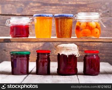 various jars of fruit jam on wooden background