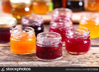 various jars of fruit jam on wooden table