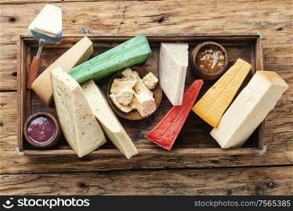 Various kind of cheese served in box on on rustic wooden table. Delicious cheese on the table