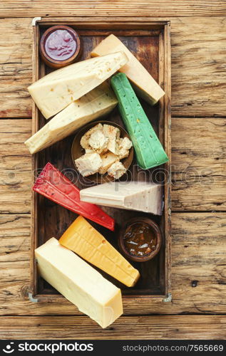 Various kind of cheese served in wooden box.Various types of cheese on rustic wooden table. Different kinds of cheeses