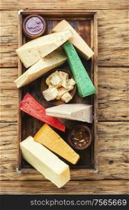 Various kind of cheese served in wooden box.Various types of cheese on rustic wooden table. Different kinds of cheeses