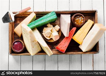 Various kind of cheese served in wooden box.Various types of cheese on white wooden table. Different kinds of cheeses