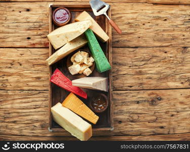 Various kind of cheese served in wooden box.Various types of cheese on rustic wooden table. Different kinds of cheeses