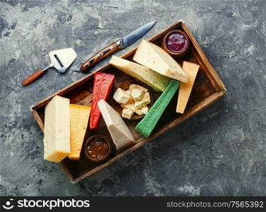 Various kind of cheese served in wooden box.Slices of cheese. Different kinds of cheeses