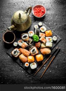 Various kinds of Japanese sushi rolls with ginger and soy sauce. On black rustic background. Various kinds of Japanese sushi rolls with ginger and soy sauce.