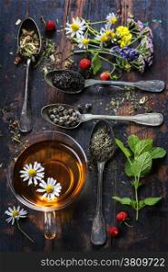 Various kinds of tea with honey, wild berry and flowers on wooden background