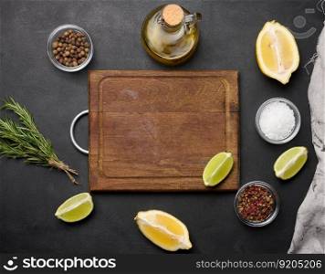 Various lemon and lime slices on a wooden board. Salt, spices and rosemary branches on a black background, top view