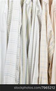 various male shirts on hangers in wardrobe close up