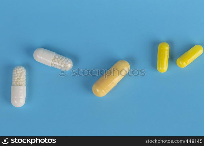 Various medicinal tablets and capsules. White and yellow medicinal tablets and capsules