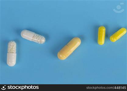 Various medicinal tablets and capsules. White and yellow medicinal tablets and capsules