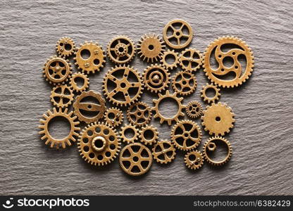 Various metal cogwheels and gear wheels over slate background