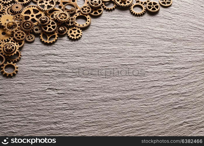 Various metal cogwheels and gear wheels over slate background