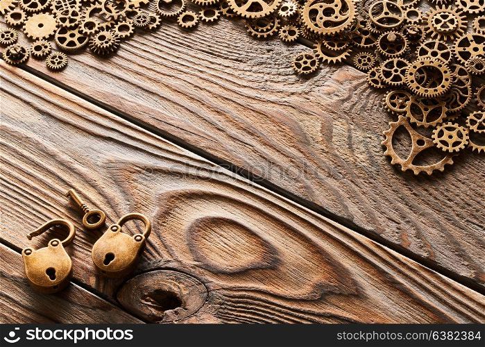 Various metal cogwheels and gear wheels with lock and key over wooden background