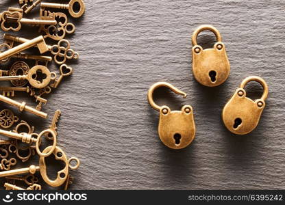 Various metal keys and locks over slate background