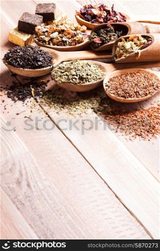 Various of dried tea in wooden scoops and spoons with copy space