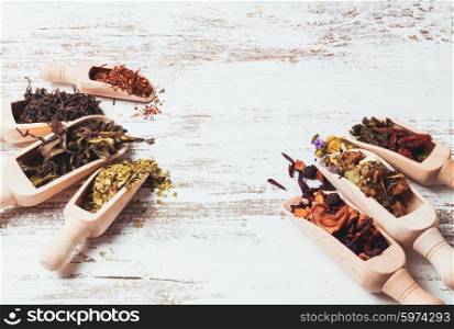Various of dried tea in wooden scoops on white shabby table. Various of tea
