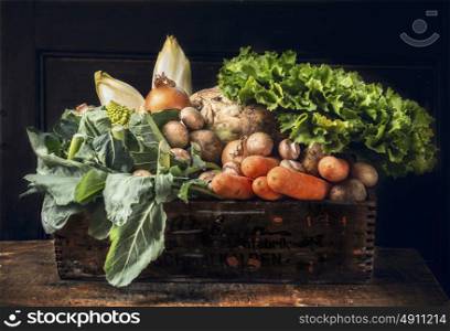 various of fresh vegetables in old box over dark wooden wall