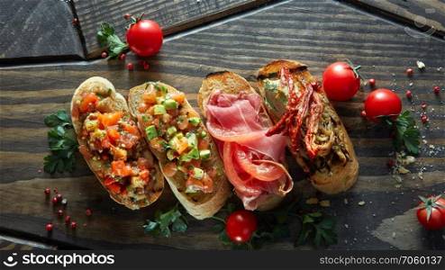 Various of mini bruschetta with tomatoes, salmon, avocado, bacon, and basil butter on wood textured background.. Various of mini bruschetta with tomatoes, salmon, avocado, bacon, and basil butter
