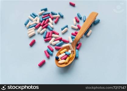 Various pills on a blue background together with a wooden spoon in which vitamins. Various pills on a blue background together with a wooden spoon in which vitamins.