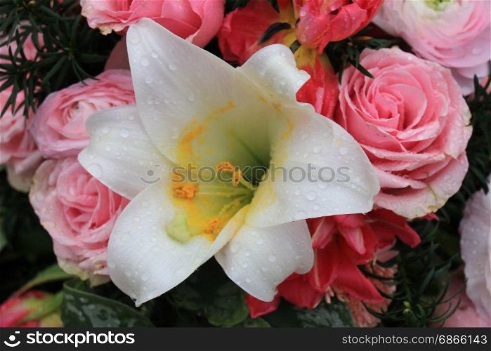 Various pink flowers and a white lily in a mixed floral arrangement