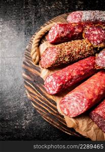 Various salami sausage on a wooden tray. On a black background. High quality photo. Various salami sausage on a wooden tray.