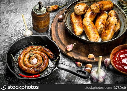 Various sausages in pans with garlic and spices. On a rustic background.. Various sausages in pans with garlic and spices.