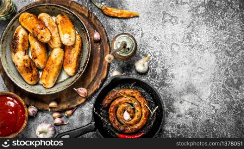 Various sausages in pans with garlic and spices. On a rustic background.. Various sausages in pans with garlic and spices.