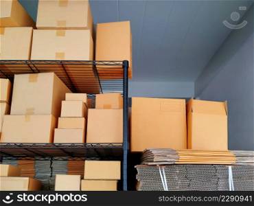 Various sizes of carton boxes on shelf display with stack of folding cardboard boxes for sale at store