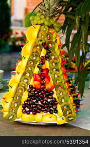 Various slices of fruits on the silver stand prepared for eating decored like form of pineapple