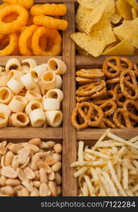 Various snacks in vintage wooden box. Onion rings,nachos, salty peanuts with potato sticks and pretzels. Suitable for beer and fizzy drinks.