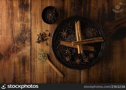 Various spices on wooden rustic board background. Pepper, cardamom, clove, cinnamon, star anis, dehydrated parsley.Flat lay