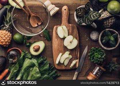 Various succulent plants and Fresh organic ingredients for salad making and wooden spoons with glass salad bowl on rustic background, top view. Flat lay with place for text. Vegan and healthy food concept