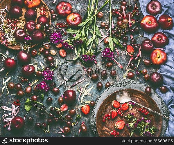 Various summer berries and fruits: strawberries, Peaches, plums, cherries, gooseberries, currants  on rustic kitchen table with flowers and plates, top view, flat lay. Organic local  food and eating