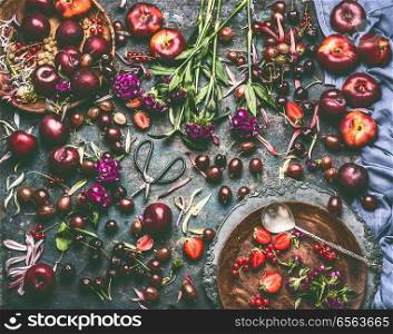 Various summer berries and fruits: strawberries, Peaches, plums, cherries, gooseberries, currants  on rustic kitchen table with flowers and plates, top view, flat lay. Organic local  food and eating