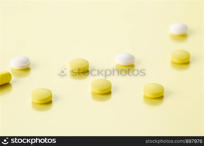 various tablets and capsules with antibiotics on a colored background. various round tablets and capsules with antibiotics on a yellow background
