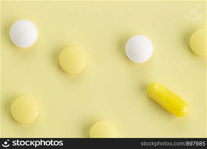 various tablets and capsules with antibiotics on a colored background. various round tablets and capsules with antibiotics on a yellow background