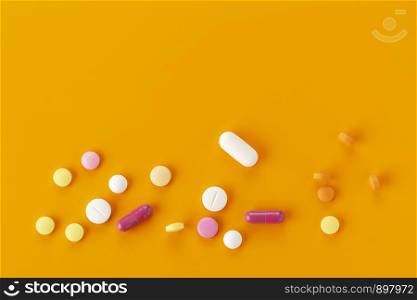 various tablets and capsules with antibiotics on a orange background. various tablets and capsules with antibiotics on a colored background