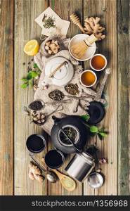 Various tea and teapots composition, dried herbal, green, black tea and matcha tea on wooden table background, flat lay