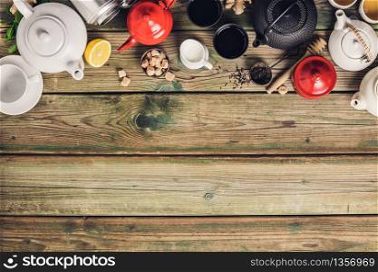 Various tea and teapots composition, dried herbal, green, black tea and matcha tea on wooden table background, flat lay, copy space