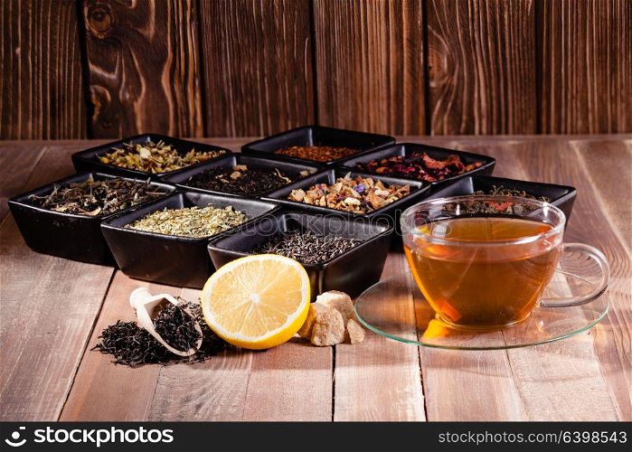 Various tea in a black ceramic bowls and a cup with hot drink. Various types of tea