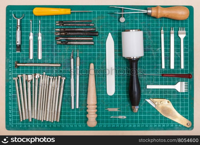 various tools for leatherwork on green self-healing mat