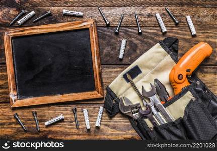 various tools toolbag near blank slate bolts wooden background
