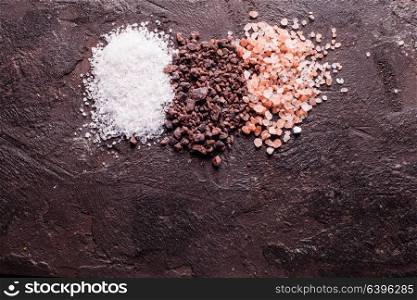 Various tupes of salts, pink Himalayas and black with sea salt on slate background. Various tupes of salts